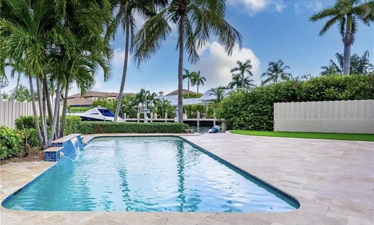 a photo of Jeweliet Tangen"s Blue pool with a deck surrounded by a palm tree that she bought without a credit or bank loan