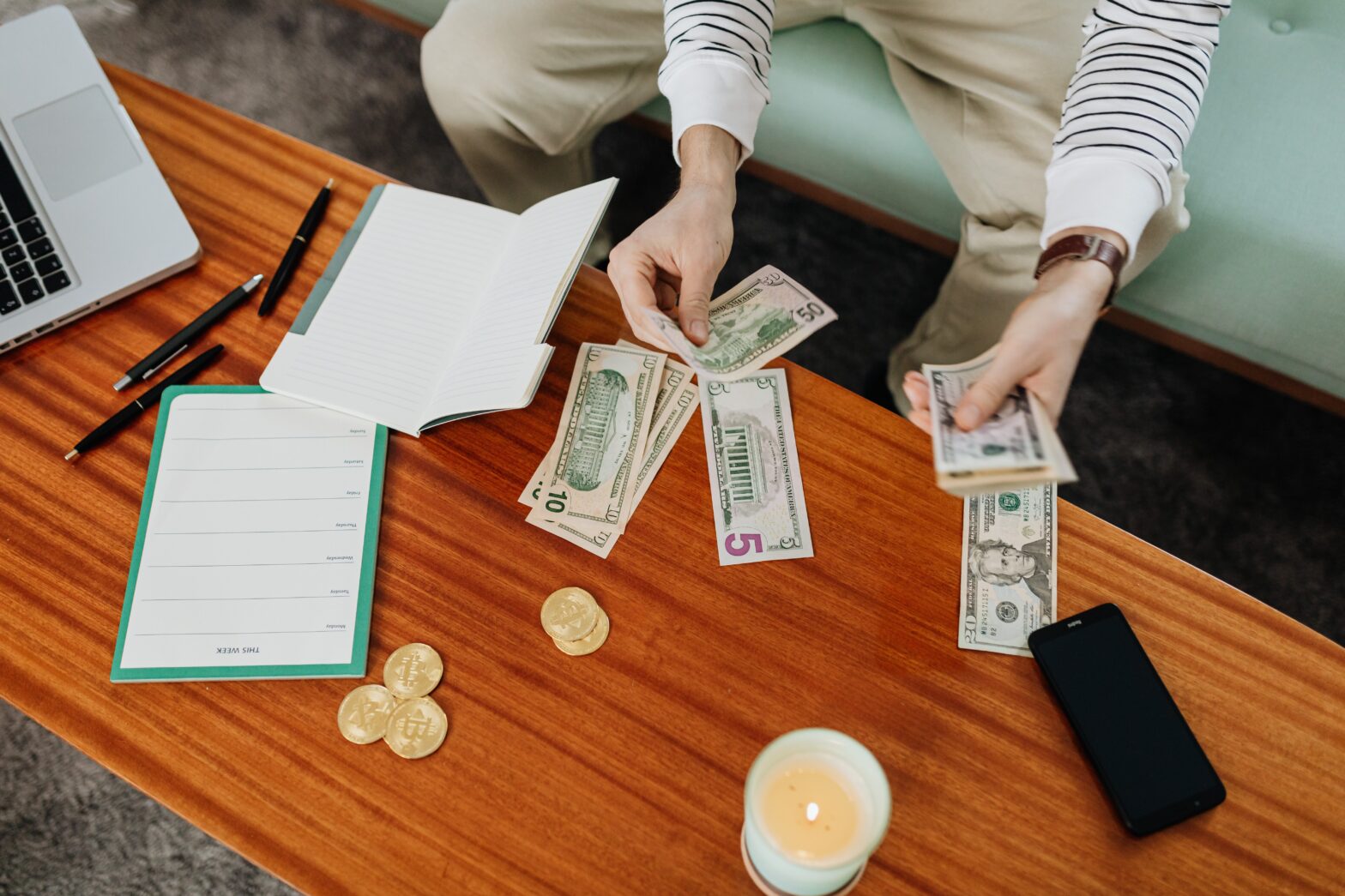 A photo of a person counting or allotting money bills on the table along with coins and notes, that can be used in private equity funds investments