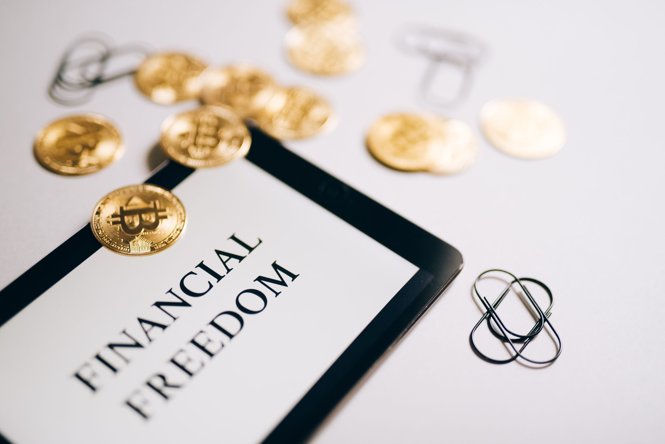 a picture showing bitcoins next to a tablet showing text that reads Financial Freedom