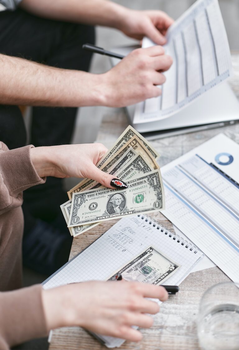 a photo of 2 set hands people, 1 is holding dollar bills and the other is holding a pen and writing on paper, which seems to sort a way to deal with inflation