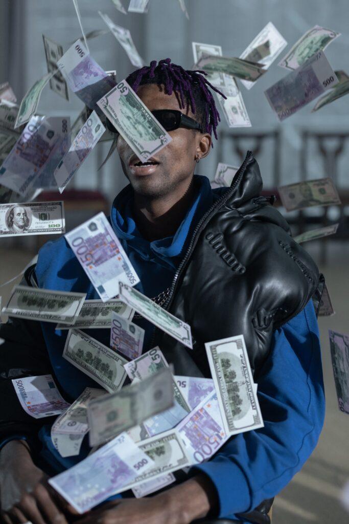 a photo of an African American man wearing black shades with money bills showering him, this is how getting a passive income feels